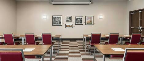A conference room with a long table, red chairs, and framed pictures on the wall.