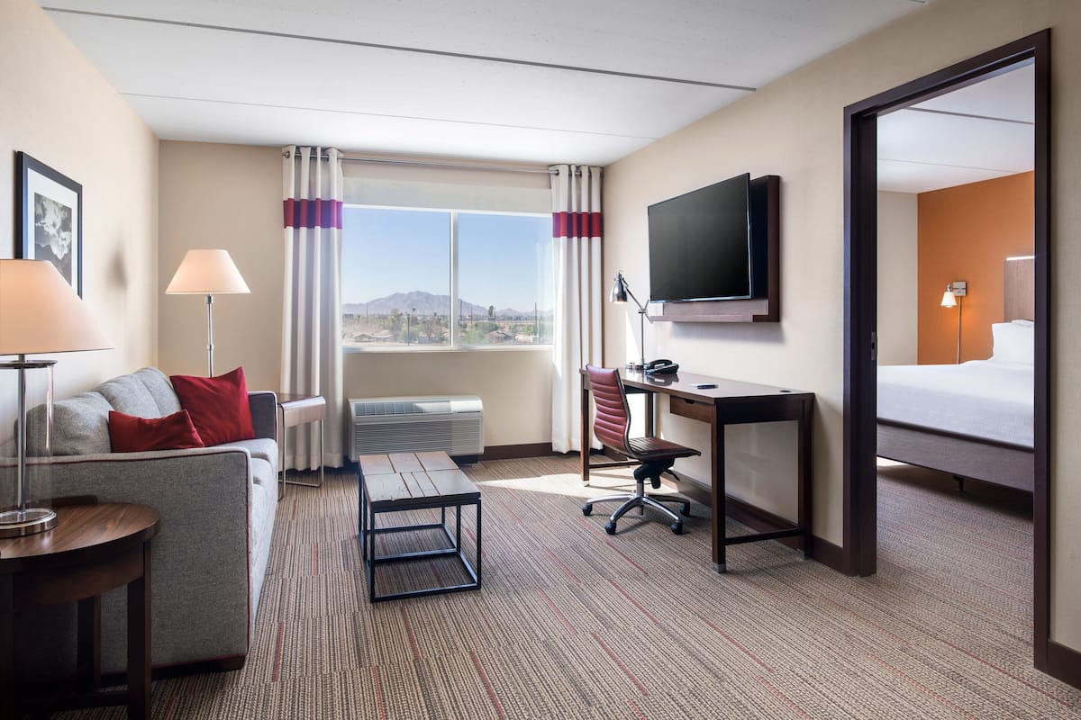 Habitación de hotel con sofá, escritorio, silla, televisor y cama.