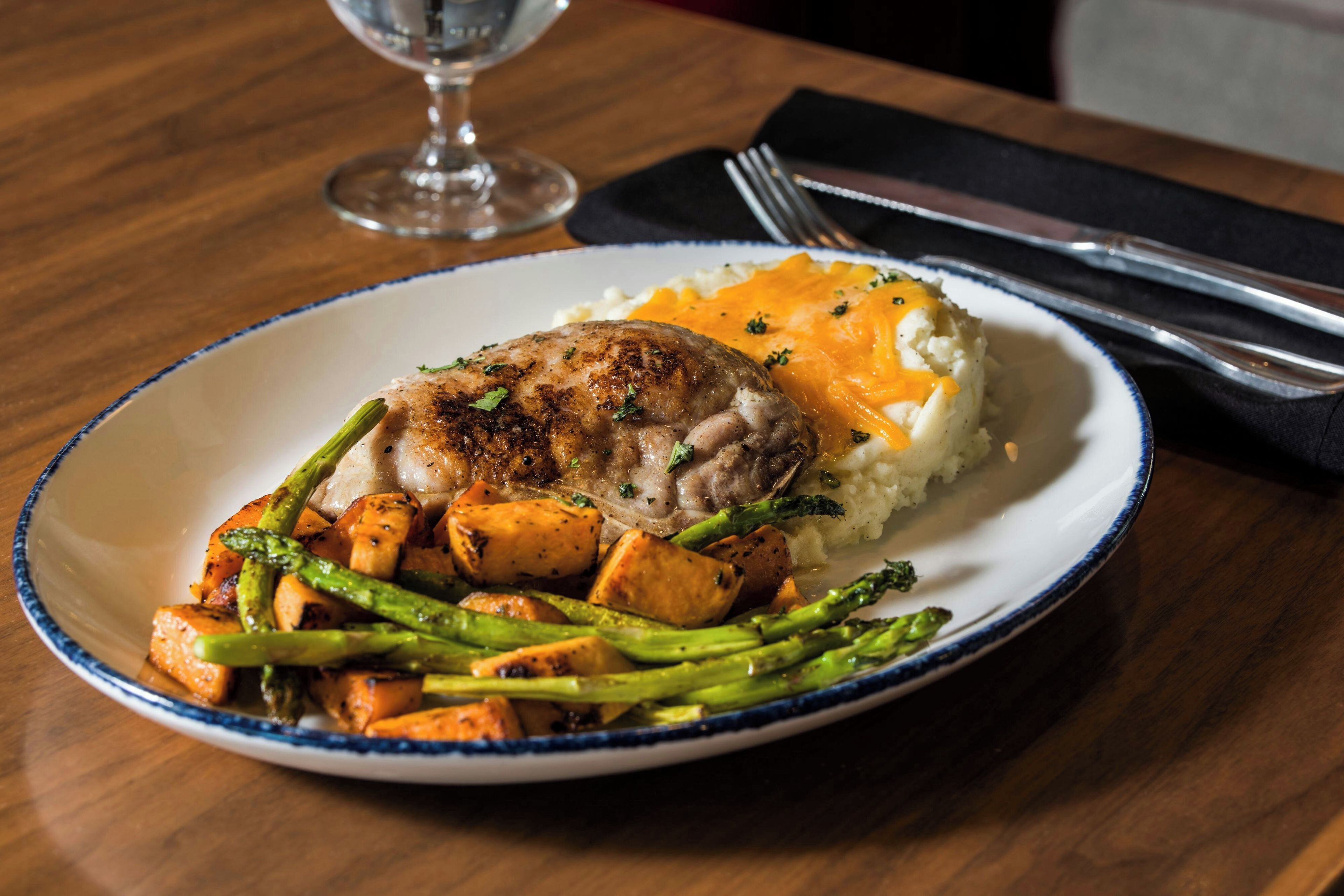 A plate with a grilled meat, mashed potatoes, and roasted vegetables.