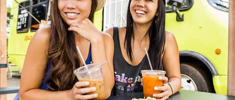 Two people sitting at a table with a plate of food and drinks.