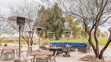 Un área de patio al aire libre con mesas, sillas y un sofá azul.