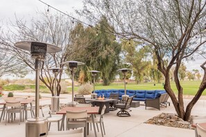 Un área de patio al aire libre con mesas, sillas y un sofá azul.