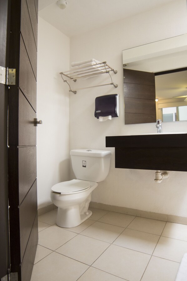 Un baño con inodoro, lavabo, espejo y toallero.