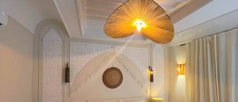 A hotel room with a large bed, a chair, a nightstand, and a wall-mounted lamp.