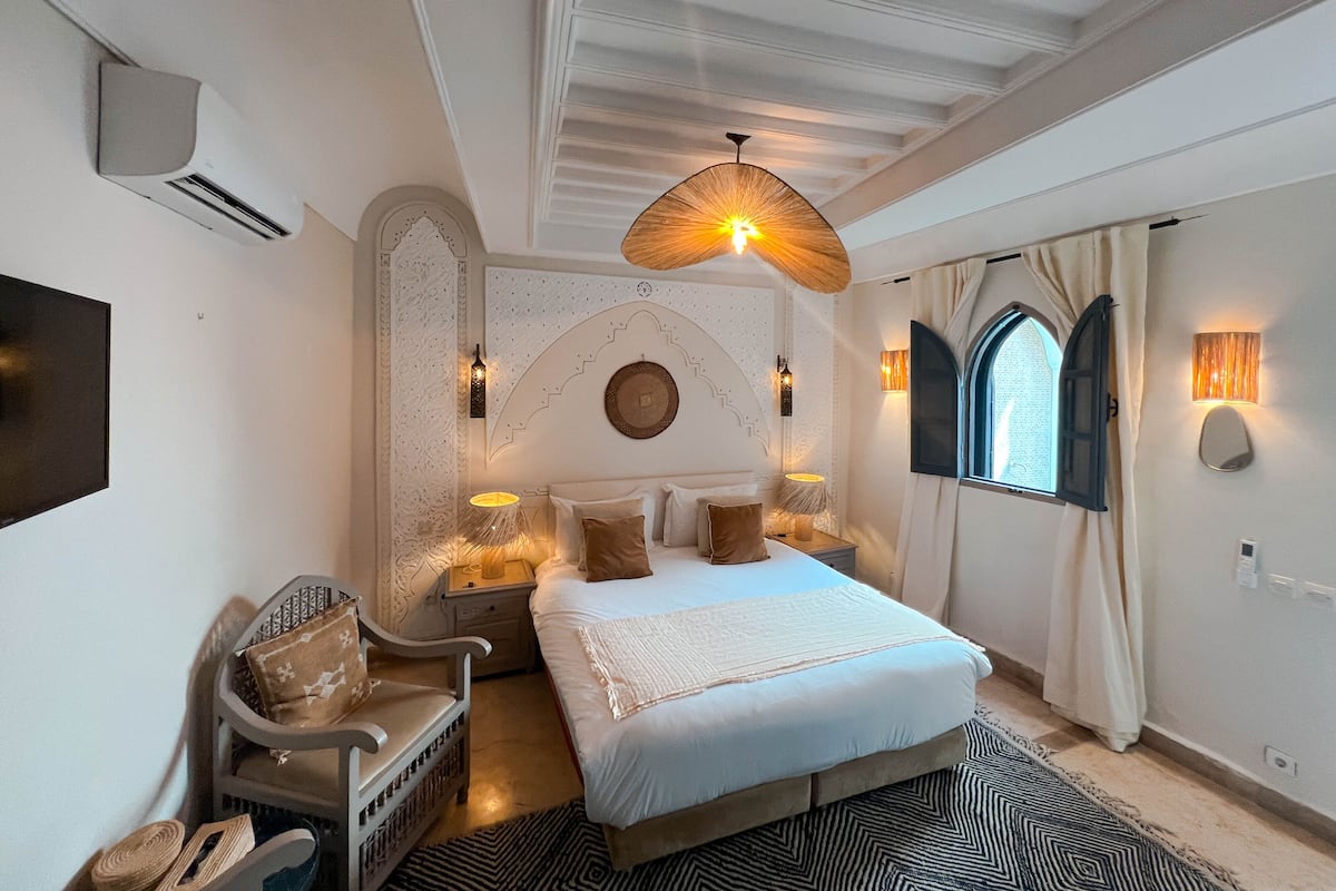 A bedroom with a bed, nightstands, a chair, and a TV.