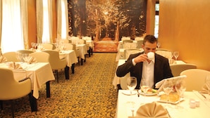 Comedor formal con mesas dispuestas para una comida, con piso alfombrado y un mural temático de bosque.