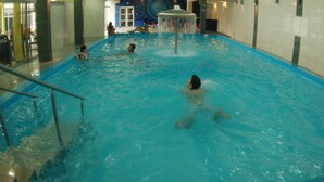 Una piscina interior con varias personas nadando y relajándose.