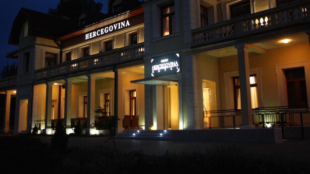 Un edificio de dos pisos con un cartel que dice "HERCEGOVINA" en la entrada.