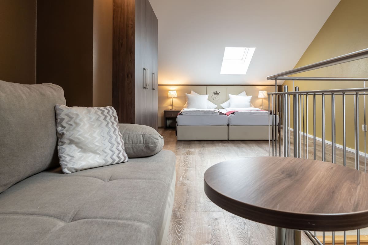 A modern bedroom with a sofa, a bed with a canopy, a round table, and a skylight.