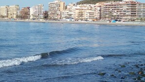 Eine Küstenstadt mit Hochhäusern, einem Strand und einer Stierstatue auf einem Hügel.