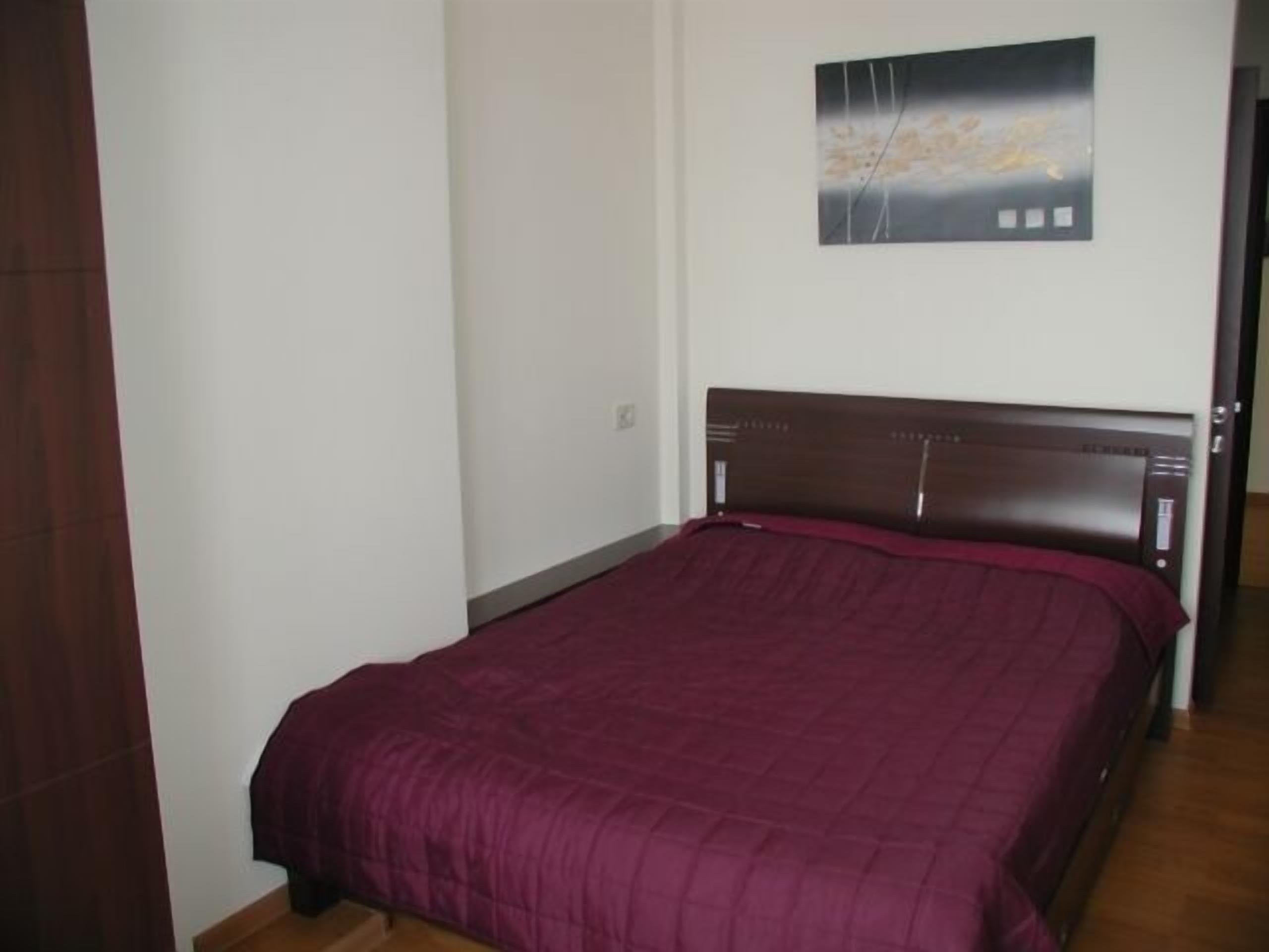 A bedroom with a bed, a wooden headboard, and a painting on the wall.