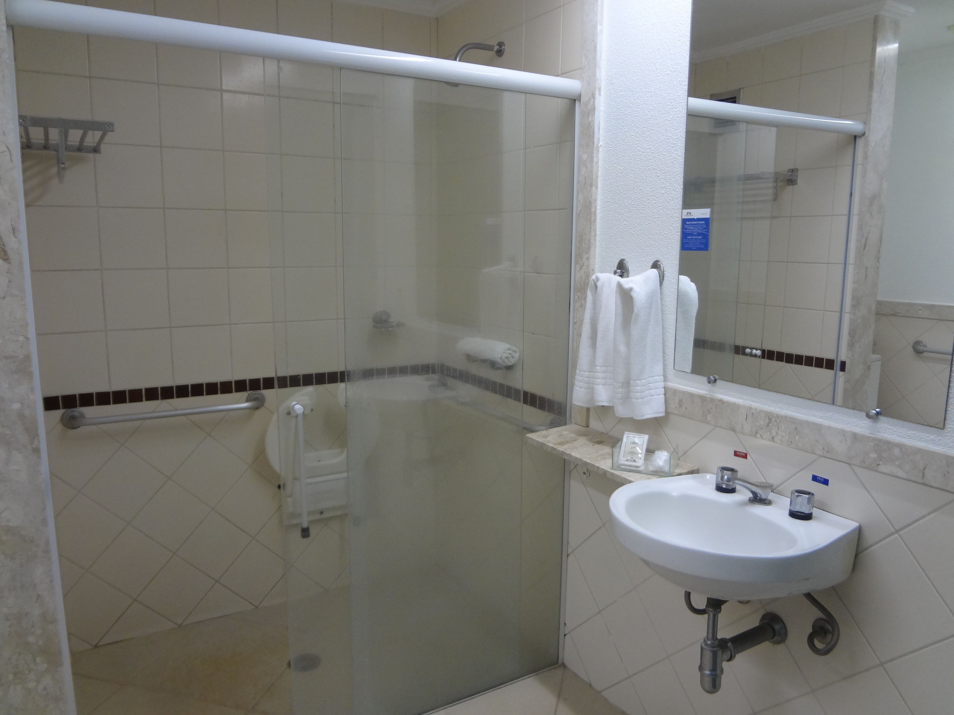 A bathroom with a glass-enclosed shower, a white sink, and a mirror.
