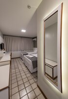 Una habitación de hotel con cama, mesita de noche y un espejo grande.