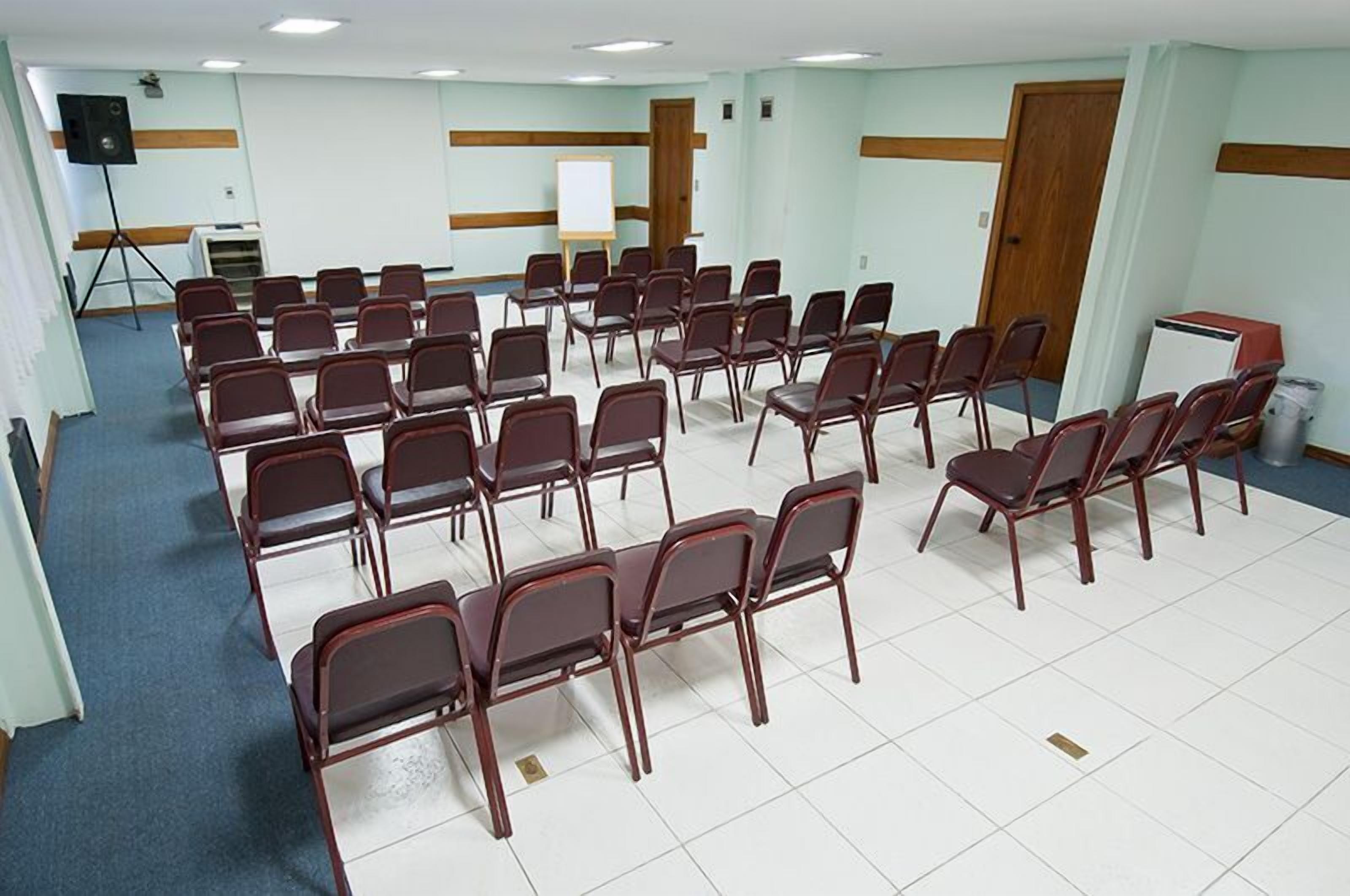 A conference room with rows of chairs, a whiteboard, and a projector on a stand.