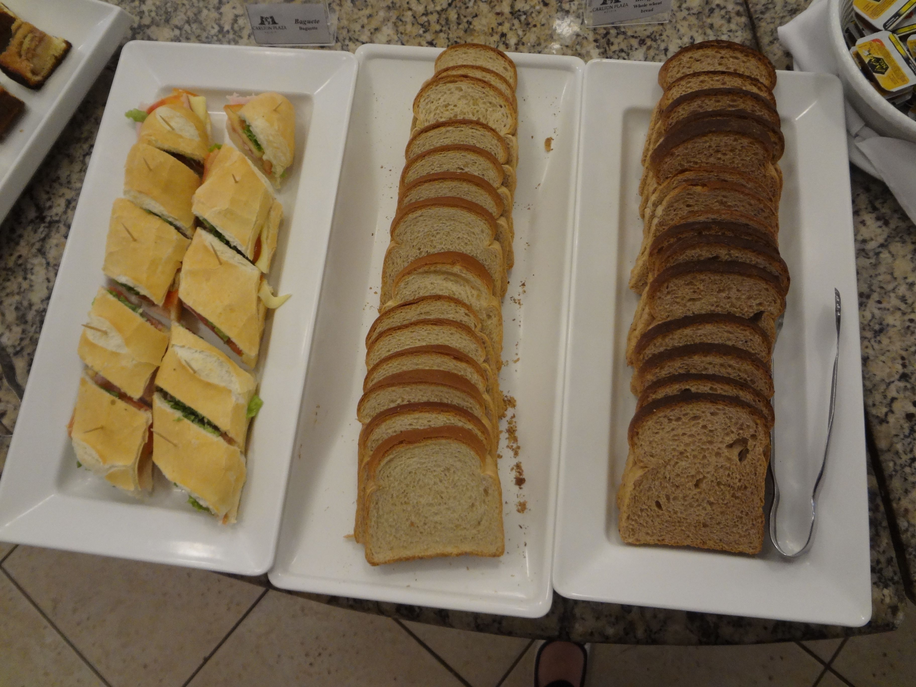 A buffet table with sandwiches and sliced bread.