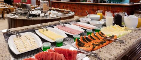 A buffet with various food items including watermelon, cheese, and tropical fruits.