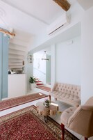 Una sala de estar moderna con un sofá, sillones, una mesa de centro y una escalera que lleva a un nivel superior.