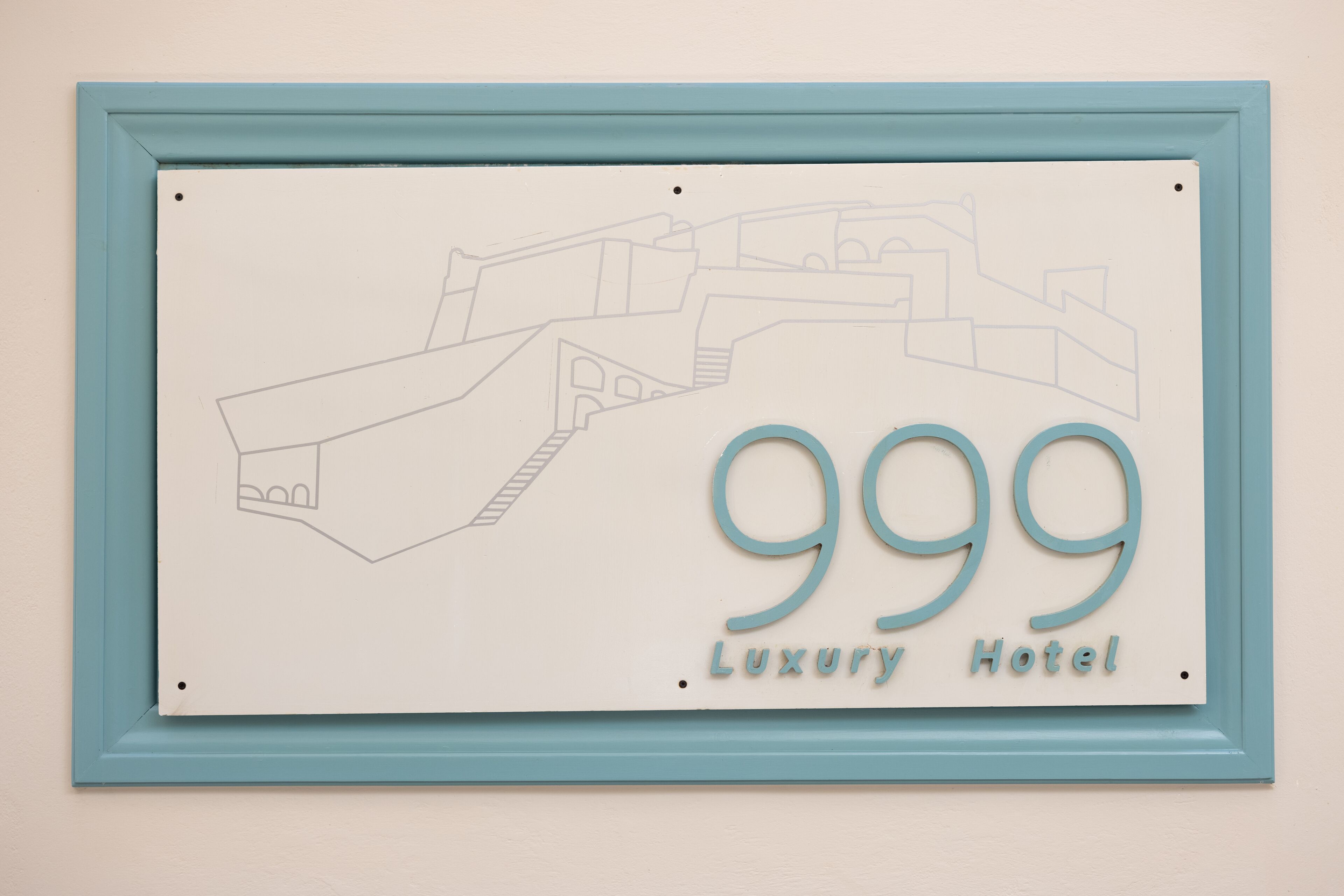 Un cartel enmarcado muestra el contorno de un edificio y el número 999, con la etiqueta 'Luxury Hotel'.
