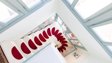 Un escalier en colimaçon agrémenté de touches de rouge et doté de grandes fenêtres laissant entrer la lumière naturelle.