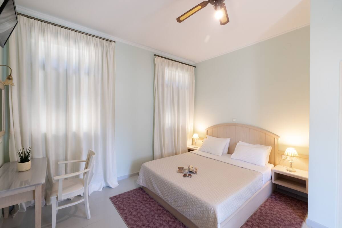 Una habitación de hotel con cama, mesitas de noche, escritorio y una silla.