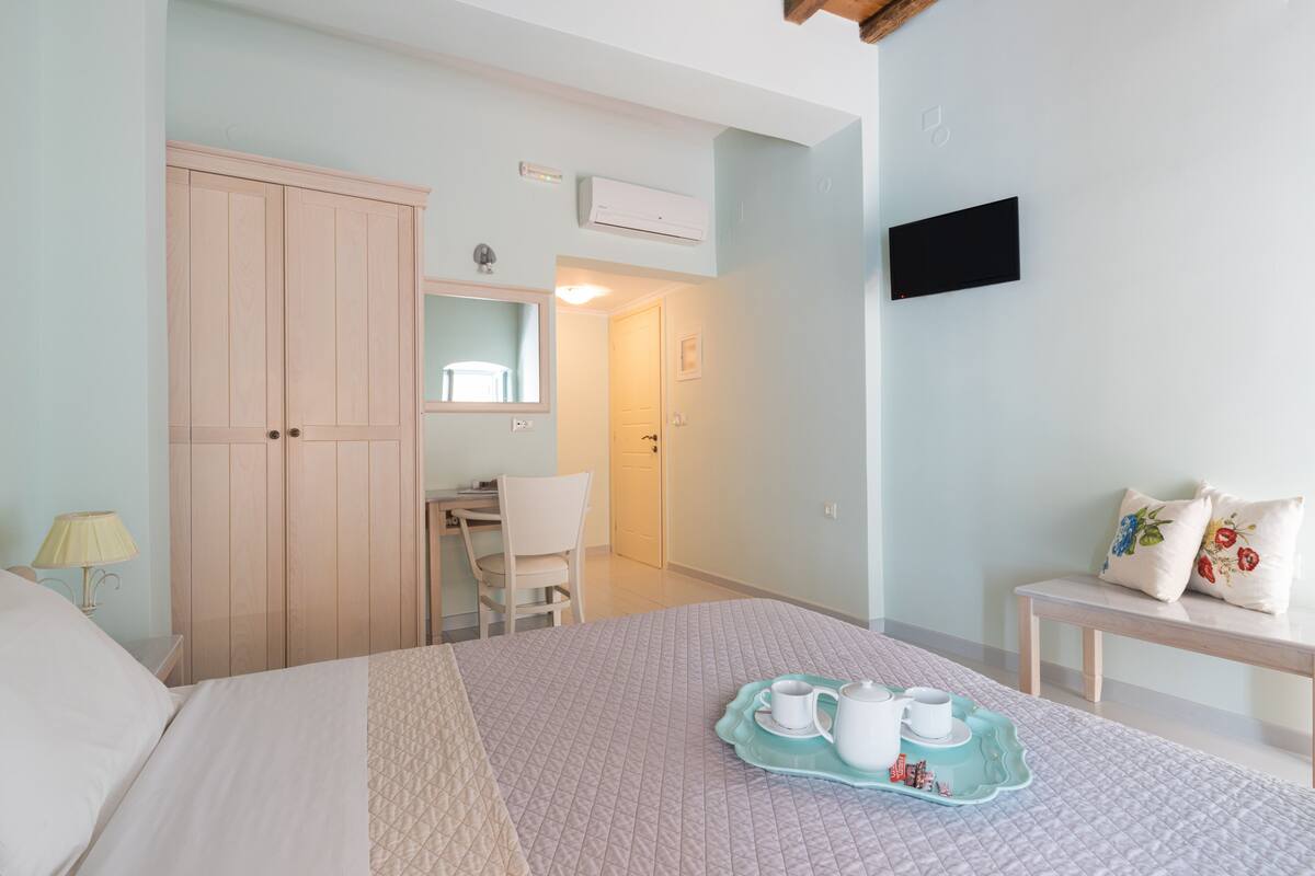 Un dormitorio con una cama, un escritorio, una silla, un televisor y una bandeja para el desayuno.