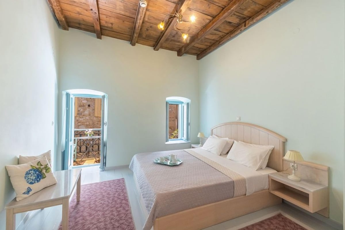 Un dormitorio con techo de madera, una cama con cabecera, mesitas de noche y una ventana.