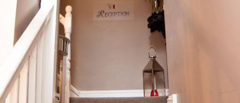 A carpeted staircase leading to a reception area with a sign above it.