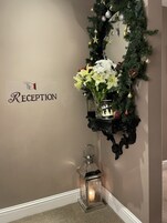 Un área de recepción con un cartel, un adorno navideño, un arreglo floral y un farol.