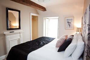 Classic design with a large bed, fireplace, and ornate mirror.