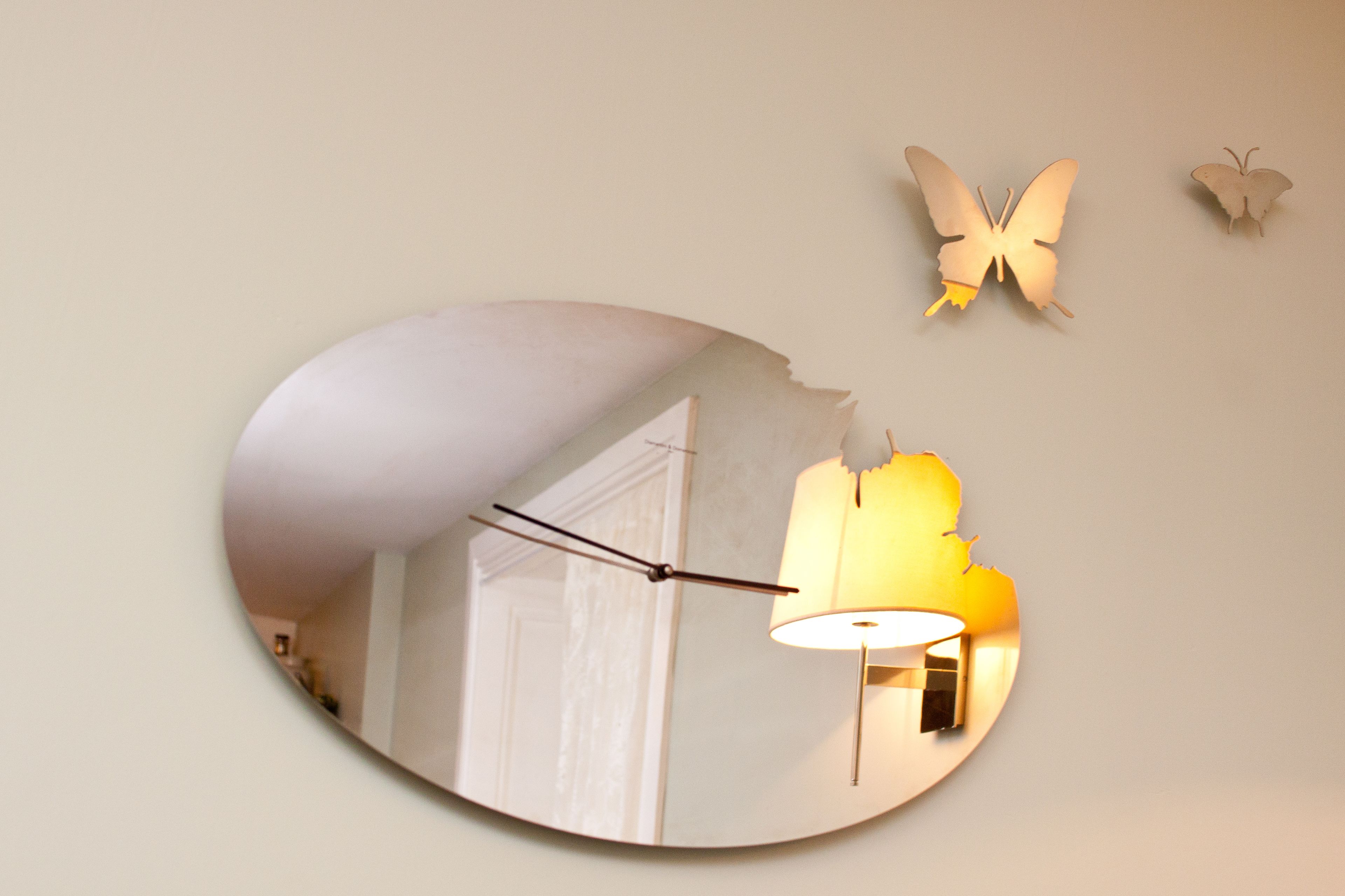Un miroir reflétant une pièce avec une lampe et une porte.