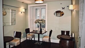 A dining area with a table and chairs, a window with blinds, a mirror, and wall-mounted lamps. - 7 Cross Street (Galway)