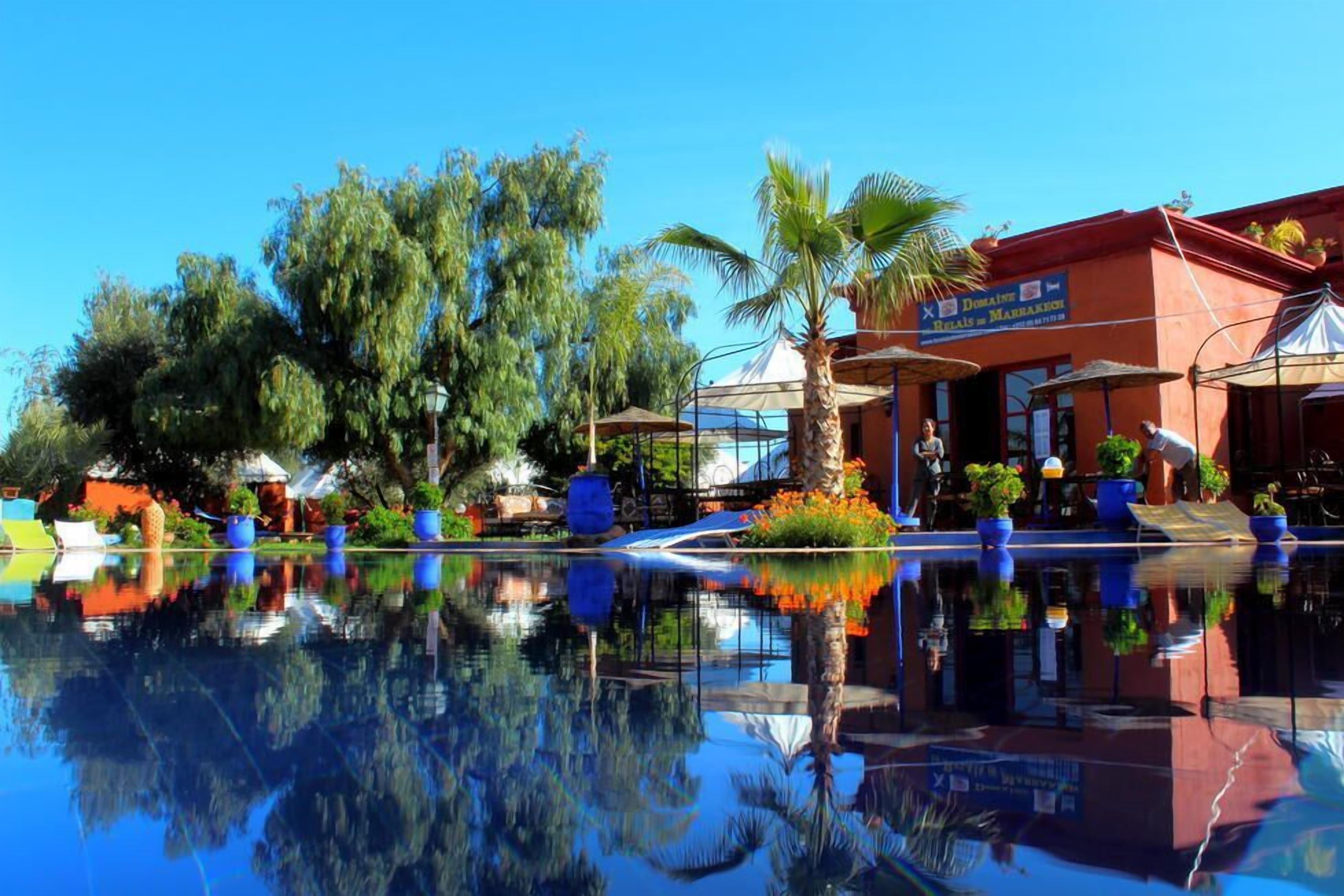A hotel with a pool reflecting trees and a building with a sign.