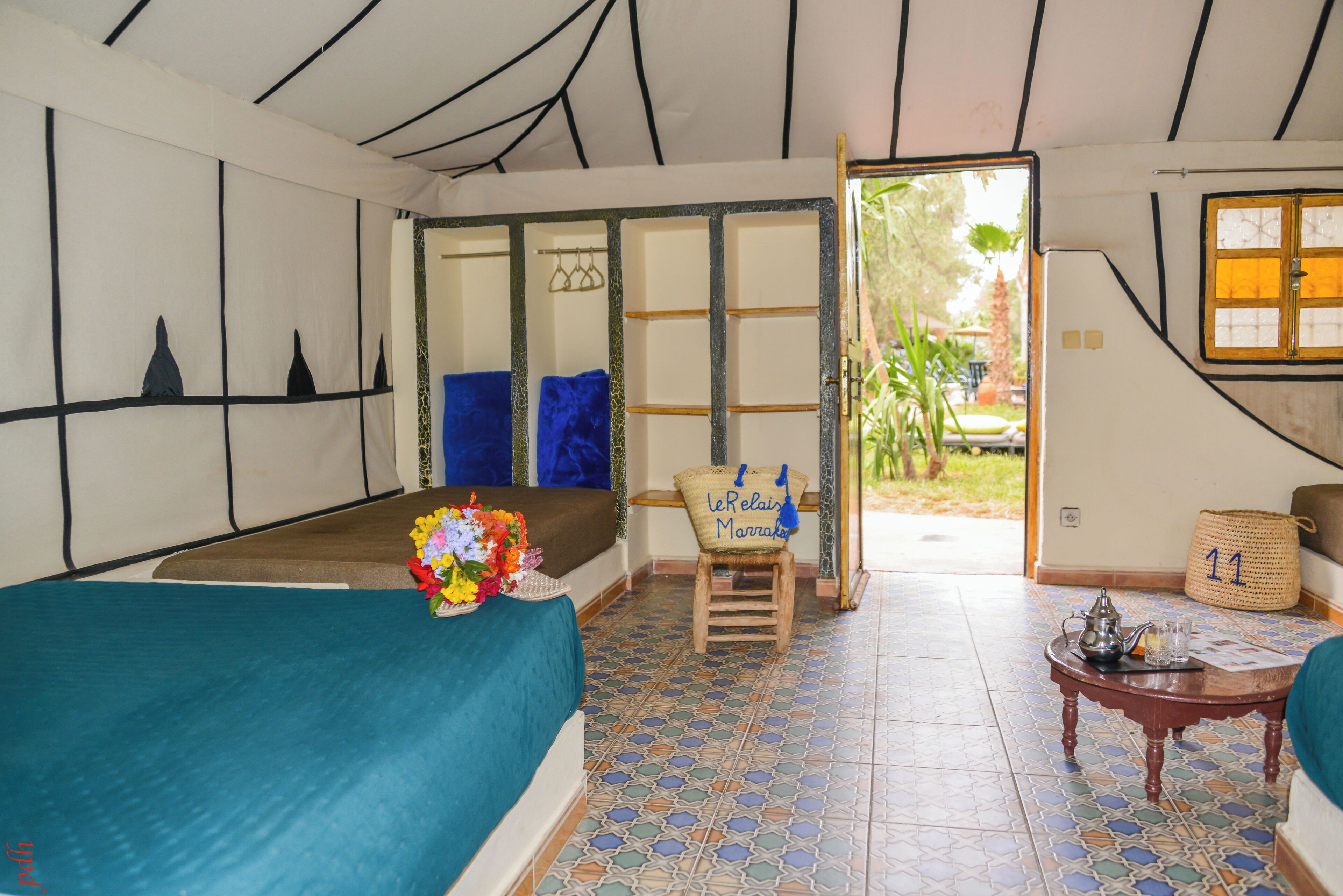 Una habitación con una cama, una mesita con un calentador de agua, una silla y vistas al exterior.