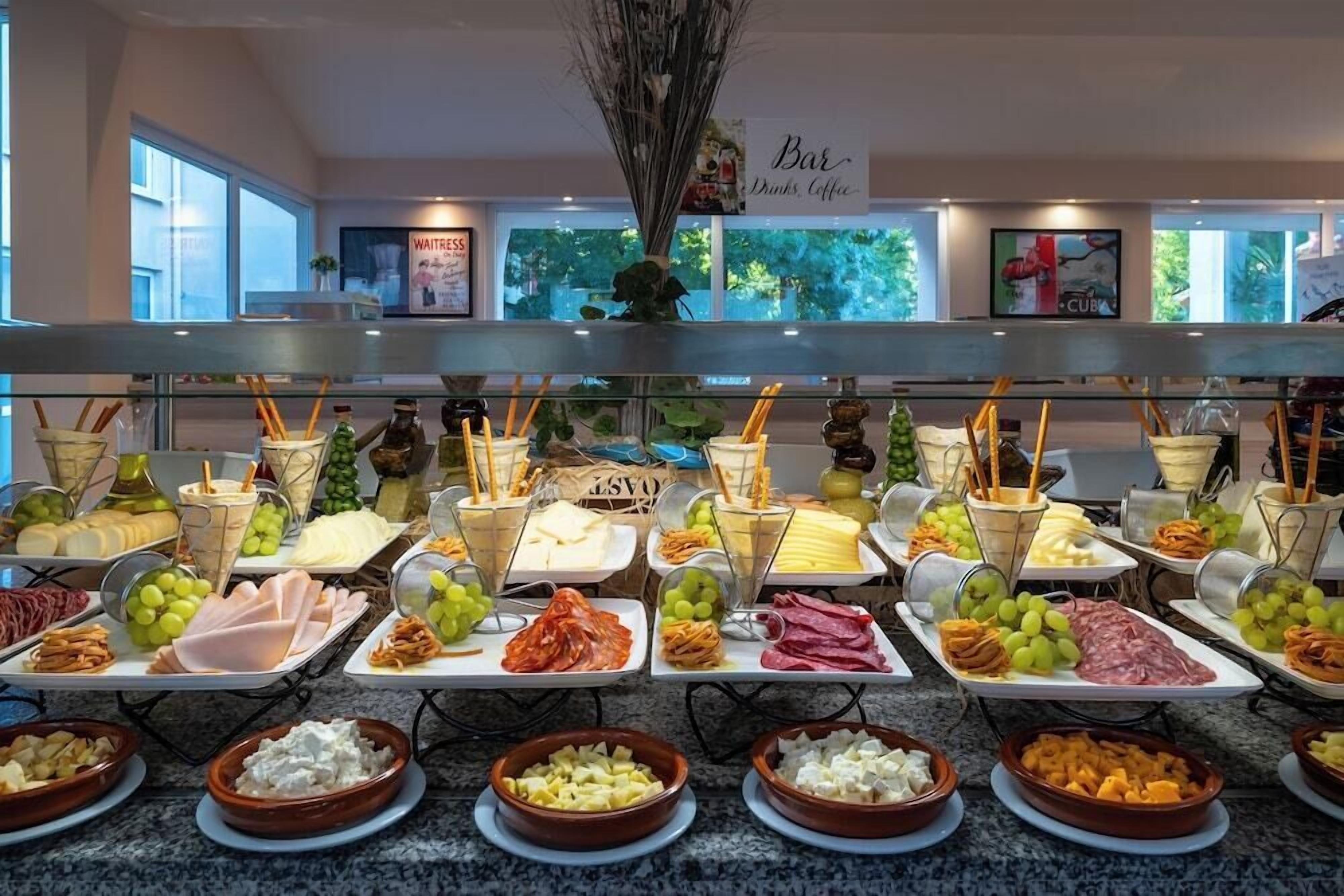 Monipuolinen buffet, jossa on tarjolla erilaisia ruokia, kuten juustoja, lihatuotteita ja hedelmiä.