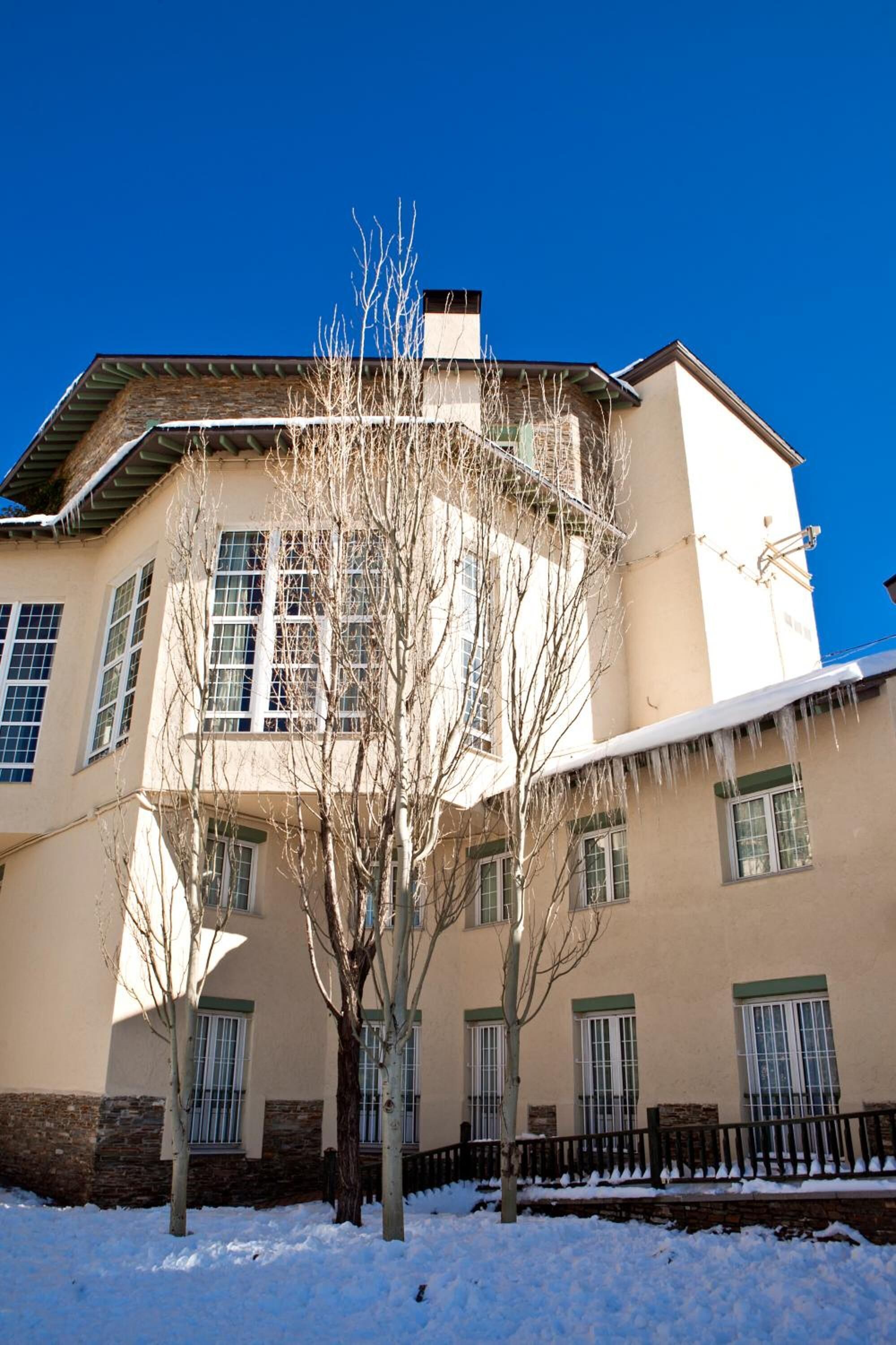 A two-story building with a beige facade, multiple windows, and a snow-covered roof.