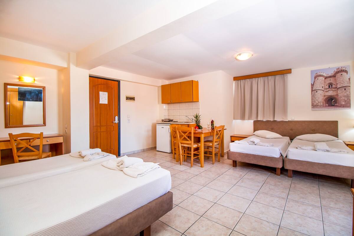 Habitación de hotel con dos camas, un escritorio, una kitchenette pequeña y un comedor.