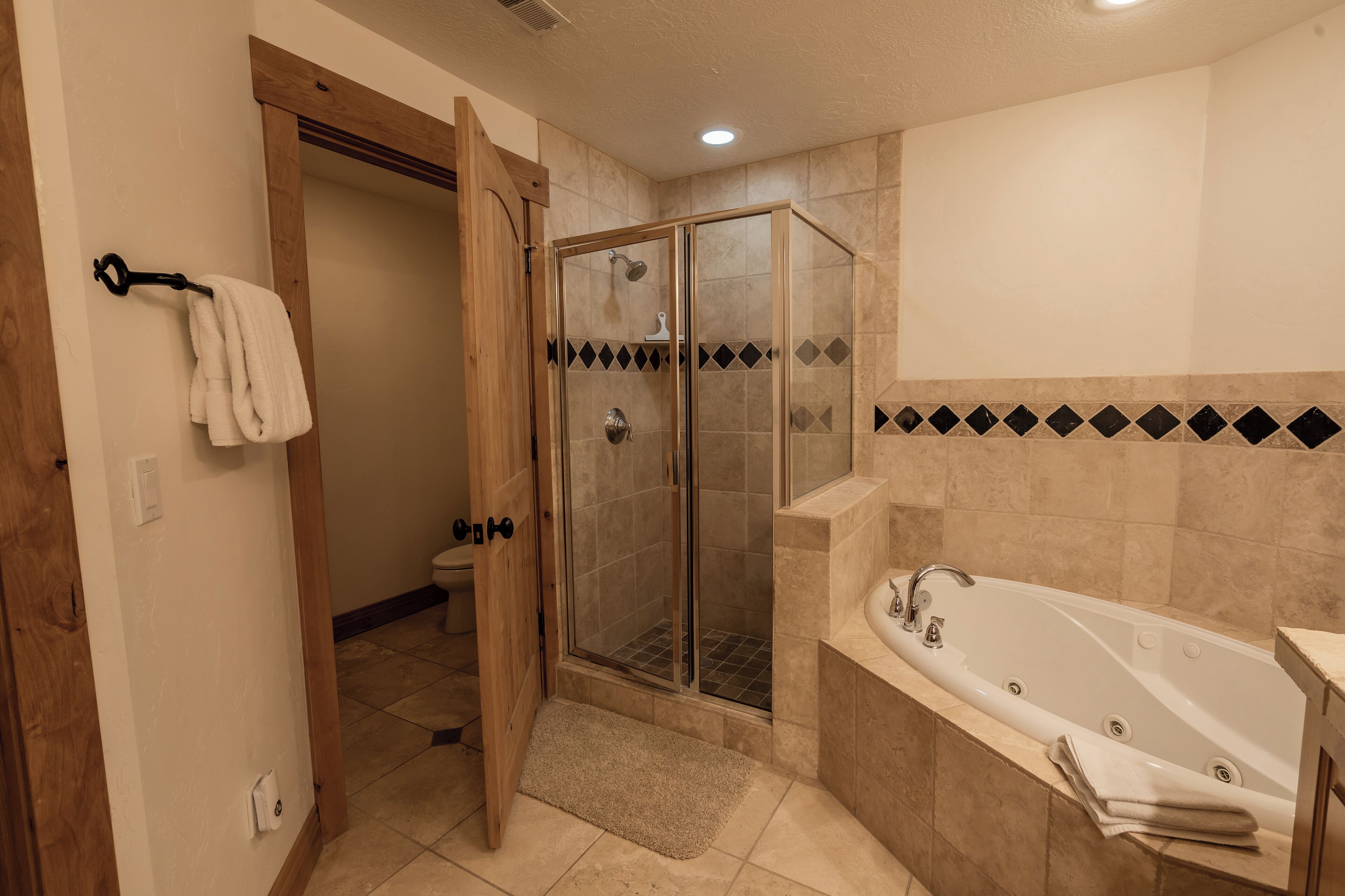 A bathroom with a glass-enclosed shower, a bathtub, and a toilet.