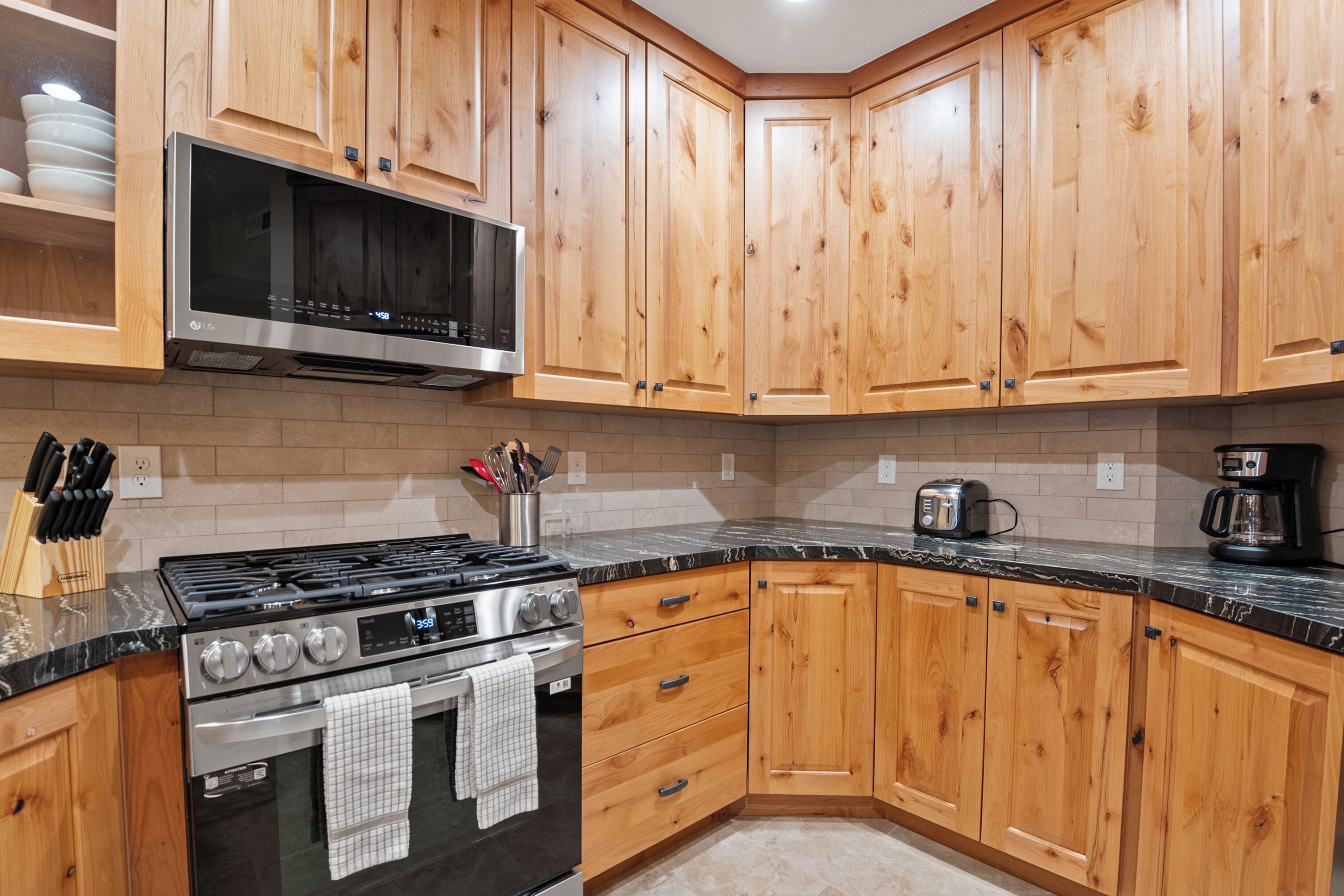 A kitchen with wooden cabinets, a stainless steel stove, and a microwave.