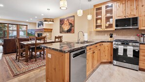 Une cuisine moderne avec des meubles en bois, un îlot central, des appareils en acier inoxydable et des luminaires suspendus.