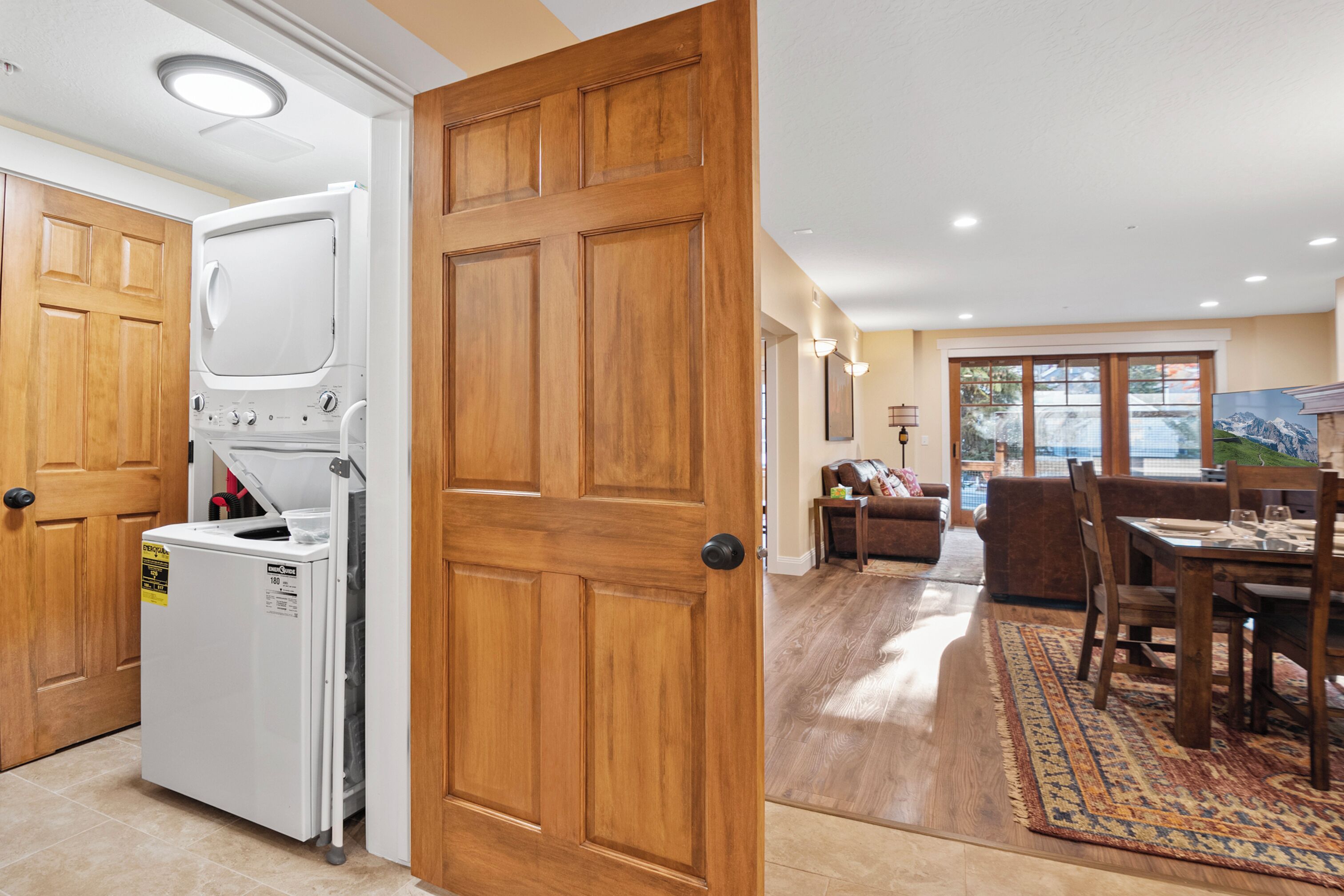 A laundry room with a washer and dryer, a wooden door, and a dining area with a table and chairs.