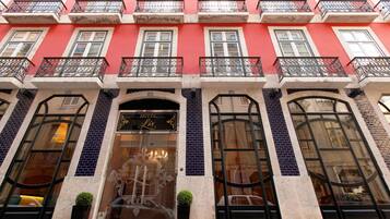 Façana d'hotel amb exterior vermell, múltiples balcons amb baranes negres i grans finestres d'arc.