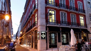 Ein rotes Mehrgeschosshaus mit Balkonen und einem Restaurant/einer Bar im Erdgeschoss.
