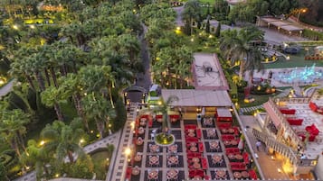 An aerial view of a resort with a central courtyard, surrounded by lush greenery and palm trees.