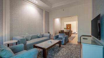 A modern living room with a sofa, armchairs, a coffee table, and a flat-screen TV.