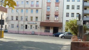 A building with multiple windows and balconies, a sign for 'El Toro Grillhaus', and parked cars on the street. - Pension Relax (Offenbach am Main)