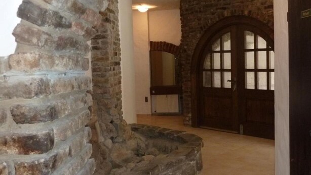 A stone archway leading to a room with a large wooden door and a radiator. - Pension Relax (Offenbach am Main)