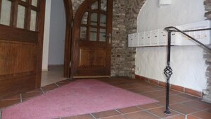 A room with a wooden door, a stone wall, a tiled floor, and a pink carpet. - Pension Relax (Offenbach am Main)