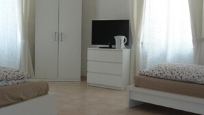 A bedroom with a bed, a wardrobe, a TV, and a bedside table. - Pension Relax (Offenbach am Main)