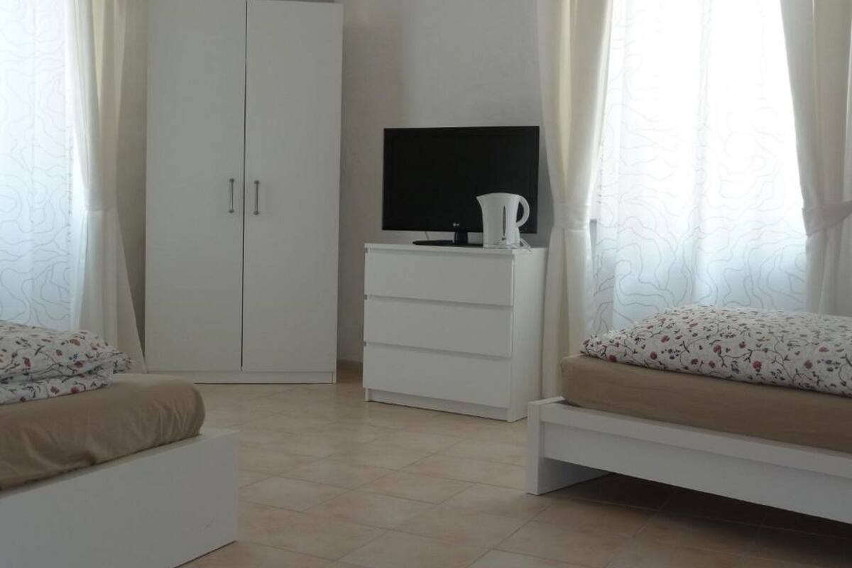 A bedroom with a bed, a wardrobe, a TV, and a bedside table.