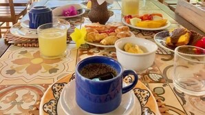 Area esterna con zona pranzo, tavolo apparecchiato per la colazione, con cornetti, frutta e caffè.